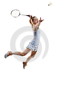 Concentrated athlete in motion, young girl, badminton player hitting shuttlecock in jump isolated over white background