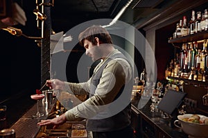 Bartender decorating pink cocktail with rose petal using tweezers