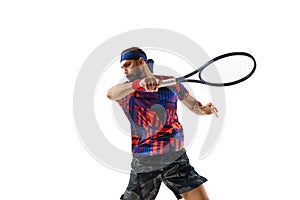 Concentrated bearded young man, tennis player hitting ball with racket, playing isolated over white background. Sport