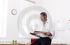 Concentrated black businessman in casual office, work with laptop