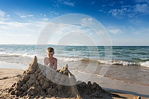 Concentrated boy building big yellow sand castle