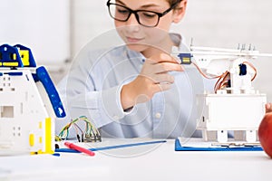 Concentrated boy constructing robot at class, closeup