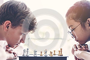 Concentrated boy and girl developing chess strategy, playing board game. Children thinking, planning moving chess. intelligent