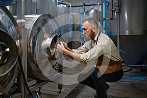 Concentrated brewer working with metallic vats in industrial brewery