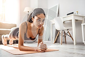 Concentrated brunette female leaning on fitness mat