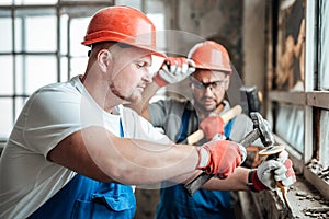 Concentrated builders remove old plaster from a brick wall