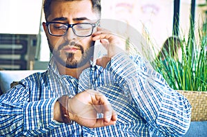 Concentrated businessman using mobile phone. Arabic businessman in glasses and beard having a phone talk seateing in the
