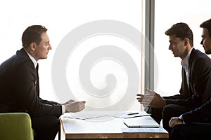 Concentrated businessmen negotiate at meeting discussing cooperation