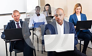 Concentrated businesspeople working on laptops during corporate seminar