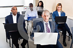 Concentrated businesspeople working on laptops during corporate seminar