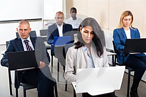 Concentrated businesspeople working on laptops during corporate seminar