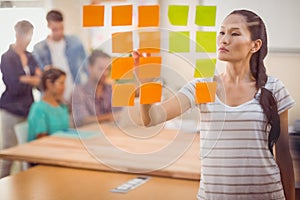 Concentrated businesswoman pointing post its on the wall