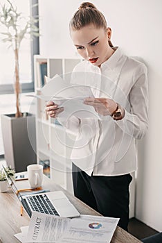 Concentrated businesswoman reading contract documents in office