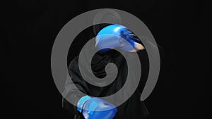 Concentrated confident Muslim woman boxing camera with angry facial expression. Portrait of young female boxer in gloves