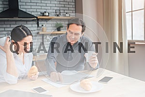 Concentrated couple sit at table in kitchen. Man point on journal page. Woman look there and smile. They have cups in