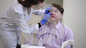 Concentrated doctor examining patient pupil visually in hospital. Professional Caucasian woman doing medical checkup of