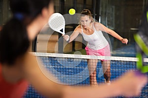 Concentrated energetic girl playing paddle tennis indoors