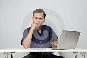 concentrated face of asian man while sitting in front of laptop computer. on isolated bakcground