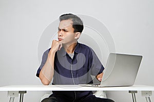 concentrated face of asian man while sitting in front of laptop computer. on isolated bakcground