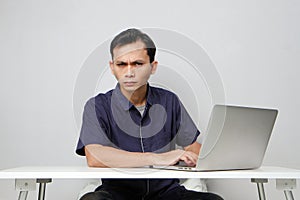 concentrated face of asian man while sitting in front of laptop computer. on isolated bakcground