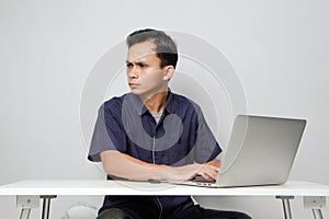 concentrated face of asian man while sitting in front of laptop computer. on isolated bakcground