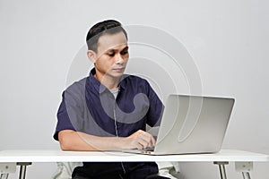 concentrated face of asian man while sitting in front of laptop computer. on isolated bakcground