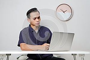 concentrated face of asian man while sitting in front of laptop computer. on isolated bakcground