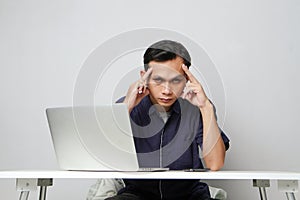 concentrated face of asian man while sitting in front of laptop computer. on isolated bakcground