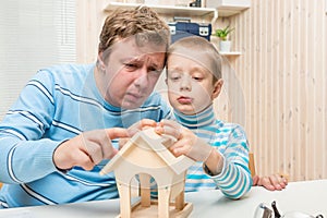 Concentrated father and son building a bird feeder