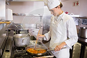 Concentrated female cook preparing food in kitchen photo