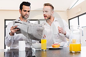 Concentrated gay couple reading newspaper