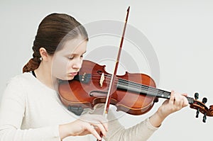 A concentrated girl playing violin owith closed eyes over white background