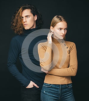 Concentrated girl standing next to a curly boyfriend. Attractive couple together. The beginning of life of a young