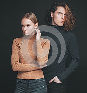 Concentrated girl standing next to a curly boyfriend. Attractive couple together. The beginning of life of a young