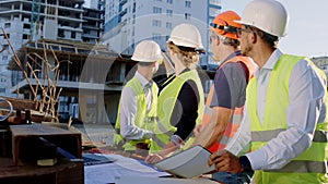 Concentrated group of diverse specialists all together analyzing the plan of construction site they looking through the