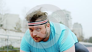 Concentrated guy obese in the stadium getting ready to start running at the starting line he are very concentrated to