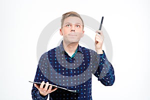 Concentrated handsome man holding clipboard and pointing up by pen