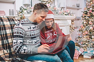 Concentrated and interested young man and woman works using laptop. They look at it. Guy pushes buttons. They wear