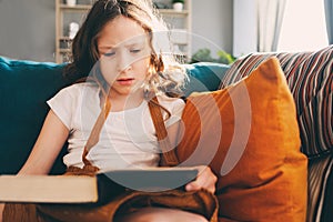 Concentrated kid girl reading interesting book at home