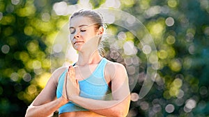 Concentrated lady yoga practitioner in blue top meditates standing in position with closed eyes