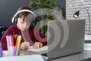 Concentrated boy doing homework while e-learning
