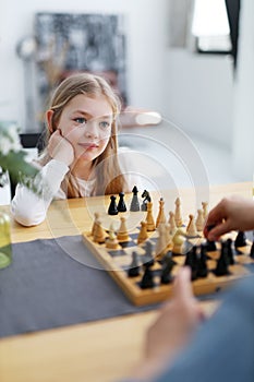 Concentrated little girl child playing chess, learning new strategies