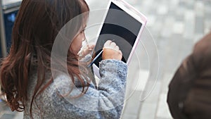 Concentrated little girl drawing stick figures on a tablet