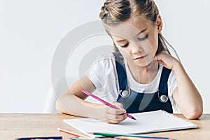 concentrated little schoolgirl drawing with color pencils