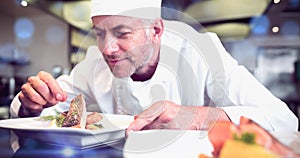 Concentrated male chef garnishing food in kitchen