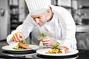 Concentrated male chef garnishing food in kitchen photo