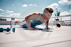 Concentrated male is doing press-ups in open air