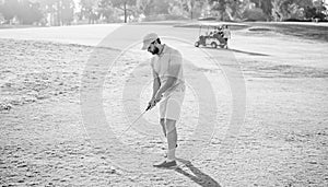 concentrated male golf player on professional course with green grass, golf swing