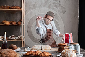 Concentrated man baker standing at bakery near bread