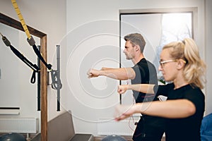 Concentrated man exercising with personal trainer